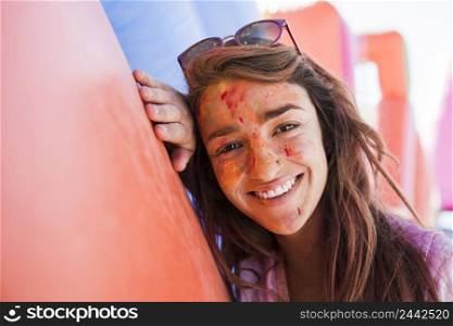 smiling portrait young woman with holi colors face powder looking camera