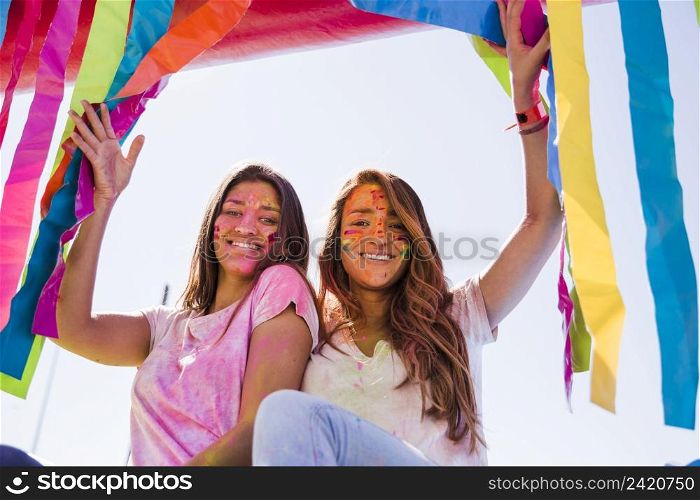 smiling portrait young women with holi color their face looking camera