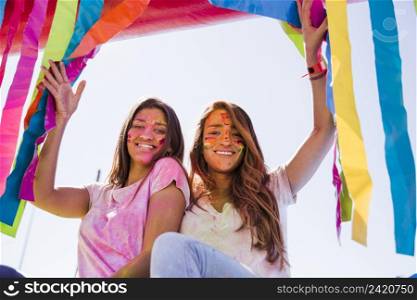 smiling portrait young women with holi color their face looking camera
