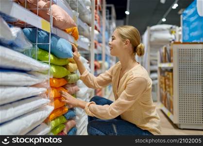 Smiling positive woman customer choosing colorful pillow in home textile shop boutique market. Smiling positive woman choosing pillow in shop