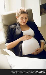 Smiling pregnant businesswoman sitting on chair at office