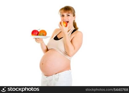 Smiling pregnant woman holding fruits in hand and eating apple isolated on white&#xA;