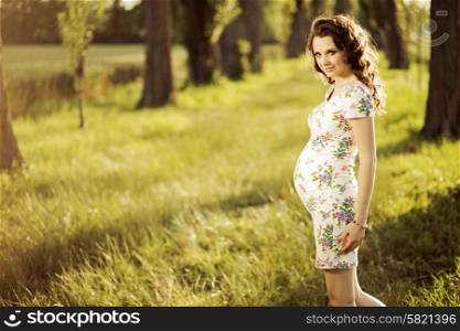 Smiling pregnant woman on the walk in the park