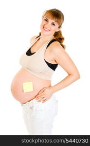 Smiling pregnant woman with blank sticky note on her belly isolated on white&#xA;