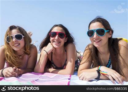smiling pretty girls best friends lying on beach while looking camera.