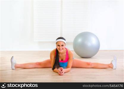 Smiling pretty gymnastic girl siting on gym split&#xA;