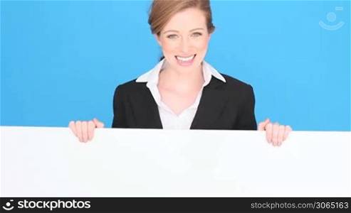 Smiling professional or businesswoman holding a large blank white sign, blue studio background