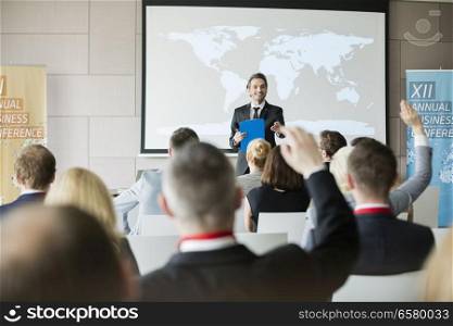 Smiling public speaker asking questions to audience during seminar