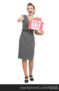 Smiling realtor showing thumbs up and home for sale sign