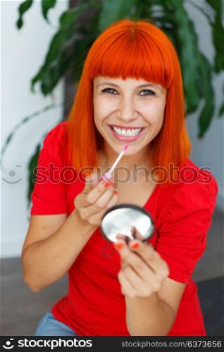 Smiling red hair girl using lipstick at home