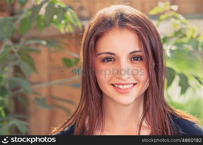 Smiling redhead teen. Front view closeup image of a smiling teenage girl outdoors against old wood plank background with leaves