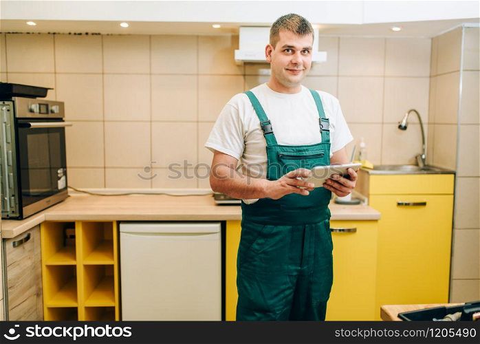 Smiling repairman in uniform holds laptop, handyman. Professional worker makes repairs around the house, home repairing service
