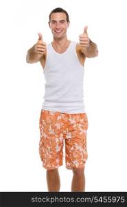 Smiling resting on vacation young man in shorts and t-shirt showing thumbs up