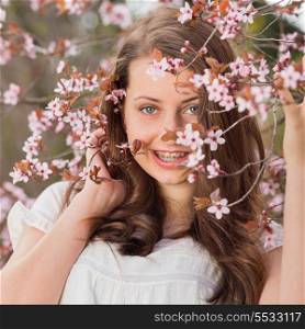 Smiling romantic girl with braces holding blossoming tree branch spring