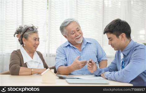 Smiling satisfied senior couple making sale purchase deal concluding contract from real estate agent,happy older family and broker shake hands agreeing to buy new house at meeting.