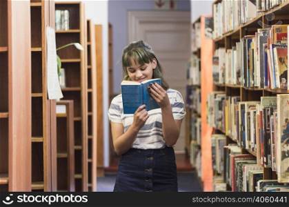 smiling schoolgirl reading book library