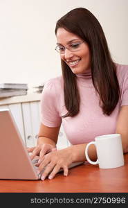Smiling secretary with coffee and laptop sitting at office
