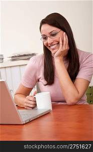 Smiling secretary with coffee and laptop sitting at office
