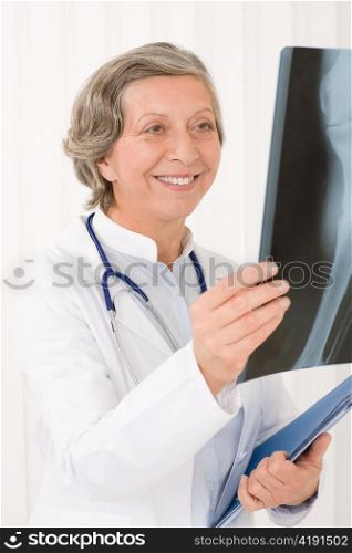 Smiling senior doctor female looking at x-ray with stethoscope portrait