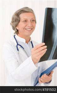 Smiling senior doctor female looking at x-ray with stethoscope portrait
