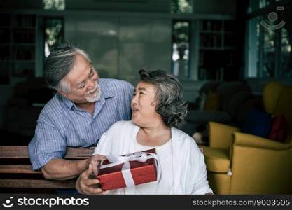 Smiling senior husband making surprise giving gift box to his wife