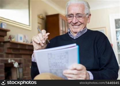 Smiling Senior Man Doing Sudoku Puzzle At Home