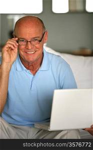 Smiling senior man on a couch with laptop