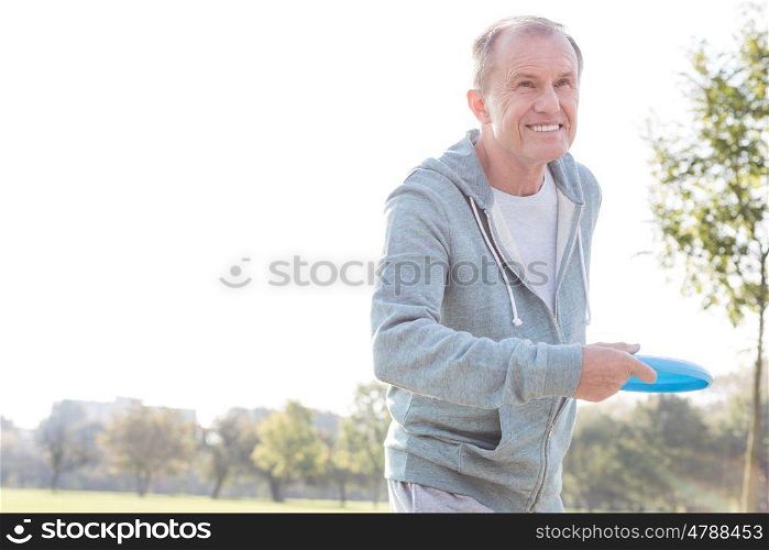 Smiling senior man throwing disc in park