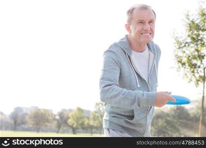 Smiling senior man throwing disc in park