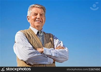 smiling Senior man with crossed hands on background sky