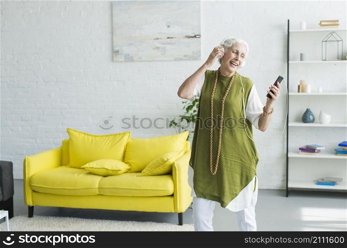 smiling senior woman listening music headphone through cellphone