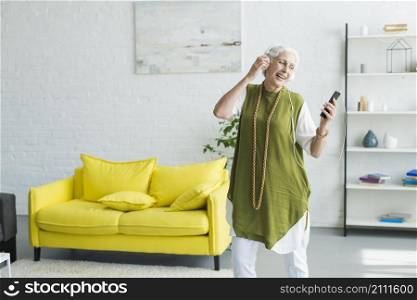 smiling senior woman listening music headphone through cellphone