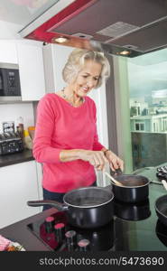 Smiling senior woman preparing food at kitchen counter