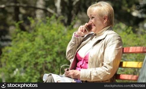 Smiling senior woman talking on cellphone outdoors
