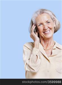 Smiling senior woman using cell phone against blue background