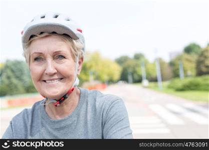 Smiling senior woman wearing cycling helmet in park