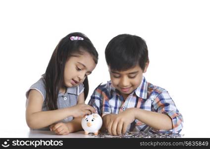 Smiling siblings counting Indian coins while sitting over white background