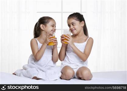 Smiling sisters holding glass of juice