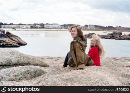 smiling sisters sitting on a bench near the sea and the shore at the Tregastel, Brittany. France
