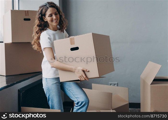 Smiling spanish woman volunteer carrying cardboard box with things for donation. Friendly happy female packing items in cartons for sending to charity. Charitable organization activity.. Smiling girl carrying carton box with things for donation, charity. Charitable organization activity