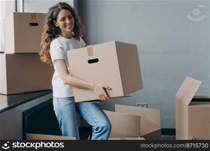 Smiling spanish woman volunteer carrying cardboard box with things for donation. Friendly happy female packing items in cartons for sending to charity. Charitable organization activity.. Smiling girl carrying carton box with things for donation, charity. Charitable organization activity