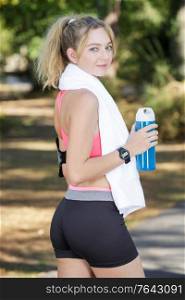 smiling sporty young woman with water bottle outdoors