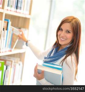 Smiling student choosing books from shelf library high school