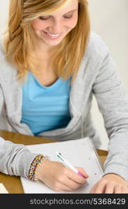 Smiling student girl looking down and writing notes