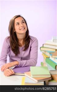 Smiling student girl stacks of books looking up purple background