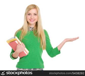 Smiling student girl with books showing something on palm