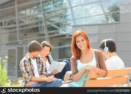 Smiling student girl with friends sitting bench outside college summer