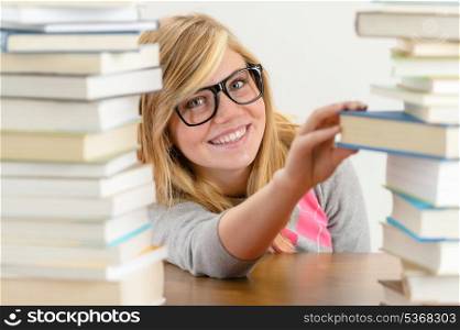 Smiling student girl with glasses take book from stack