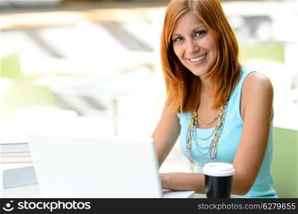 Smiling student girl with laptop at college looking at camera