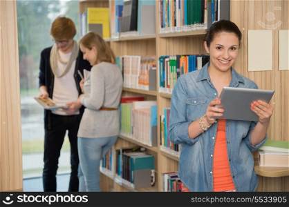 Smiling student holding tablet with friends in background at library